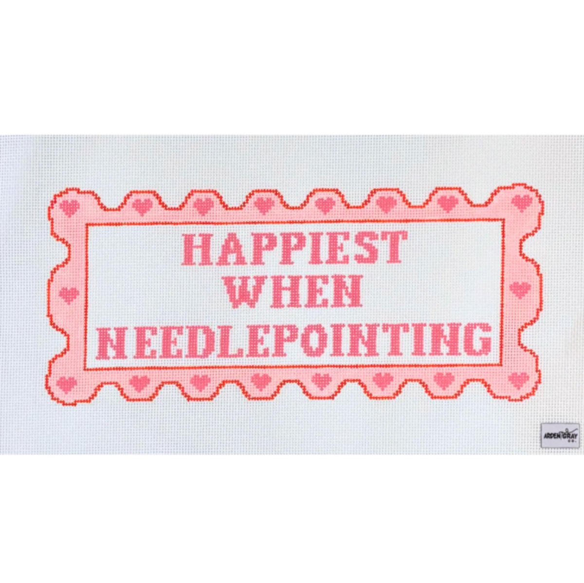 A rectangular needlepoint canvas featuring the phrase 'HAPPIEST WHEN NEEDLEPOINTING' in pink lettering inside a scalloped pink border with small heart motifs, shown on a plain white background.