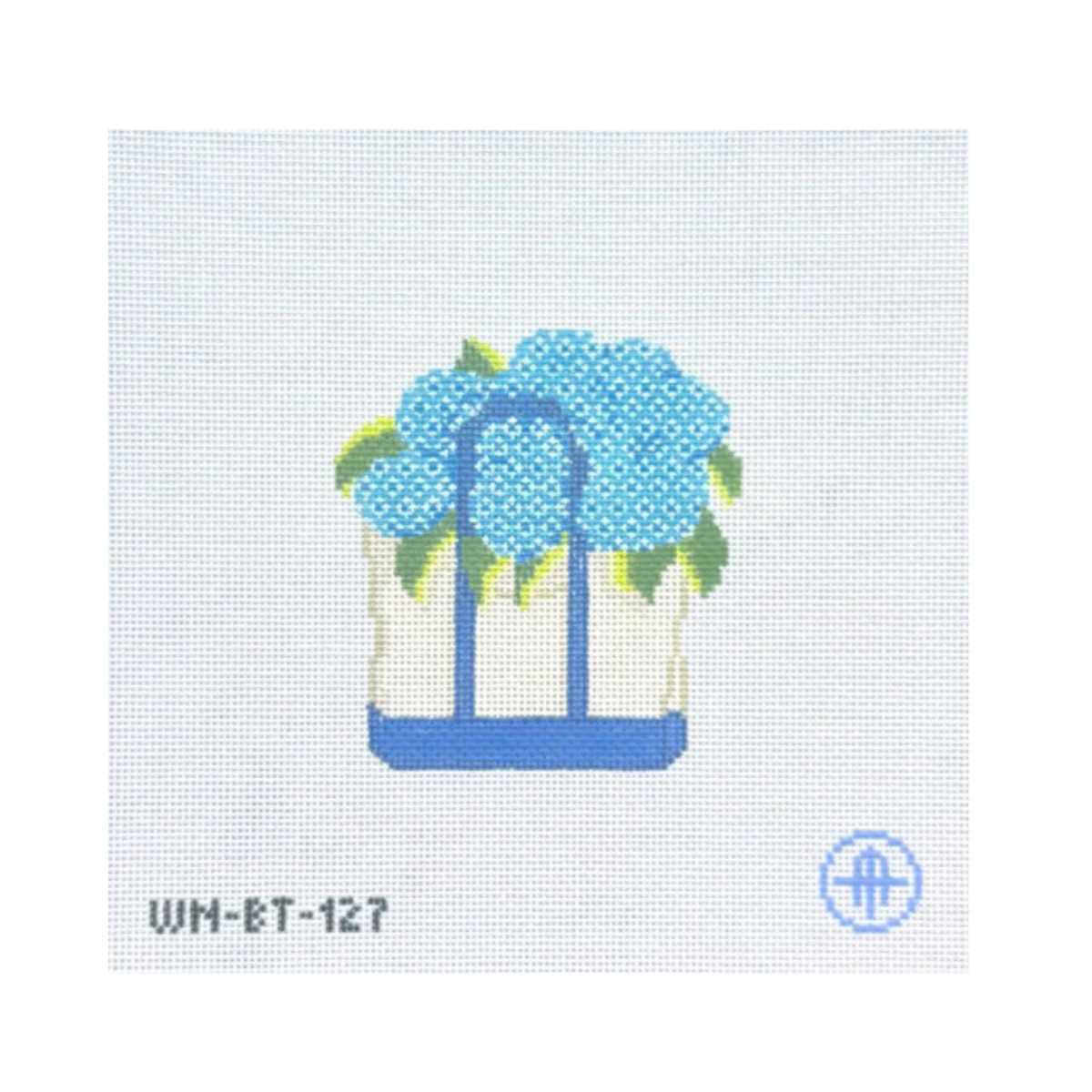 A needlepoint canvas design featuring a white basket with blue handles and a blue base, filled with light blue hydrangea flowers and green leaves. The text 'WM-ET-127' is printed in black at the bottom left, and a blue circular logo is at the bottom right, all on a white grid canvas background.