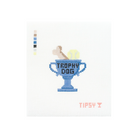 A cross-stitch style design on a white fabric background featuring a blue trophy cup with the words 'TROPHY DOG' in black, a tan dog figure climbing out of the cup, a yellow ball, and small pink text reading 'TIPSY T' below. A vertical color swatch strip appears on the left side.