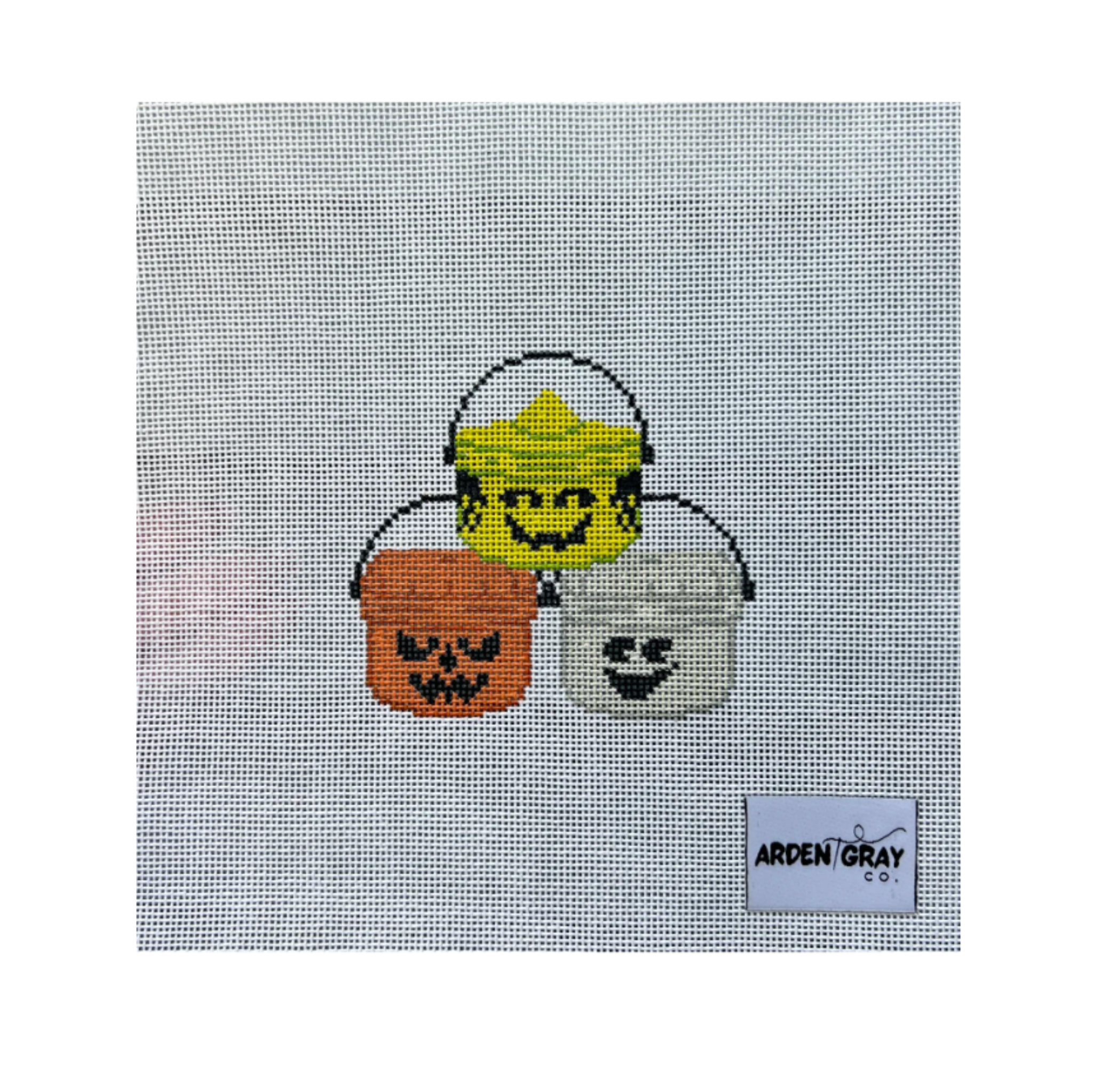 A needlepoint canvas featuring three Halloween buckets: a yellow bucket with a smiling face, an orange bucket with a pumpkin face, and a white bucket with a ghost face. The canvas has a visible 'ARDEN GRAY CO.