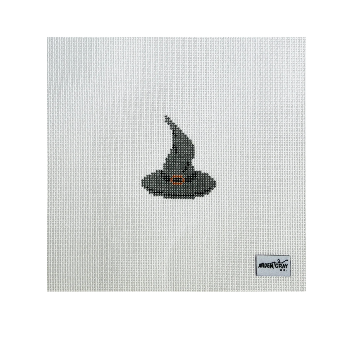 A needlepoint canvas featuring a small pixelated black witch hat with a tiny orange accent, on a white mesh grid with the 'Angels & Art' brand logo in the bottom right corner.