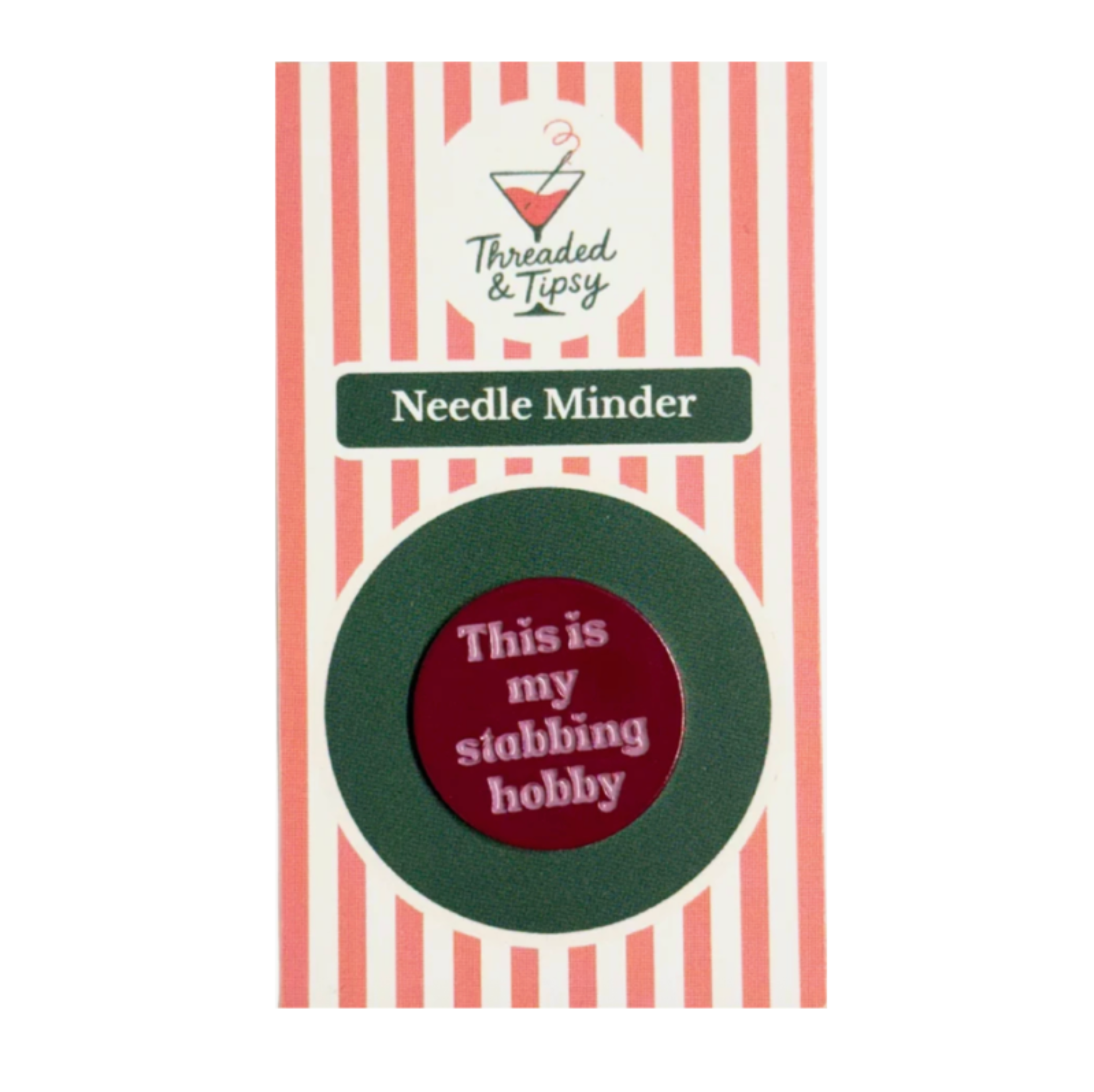 A circular enamel pin with the text 'This is my stabbing hobby' in white on a dark red center, surrounded by a dark green ring, mounted on a pink and white striped backing card labeled 'Threaded & Tipsy Needle Minder'.